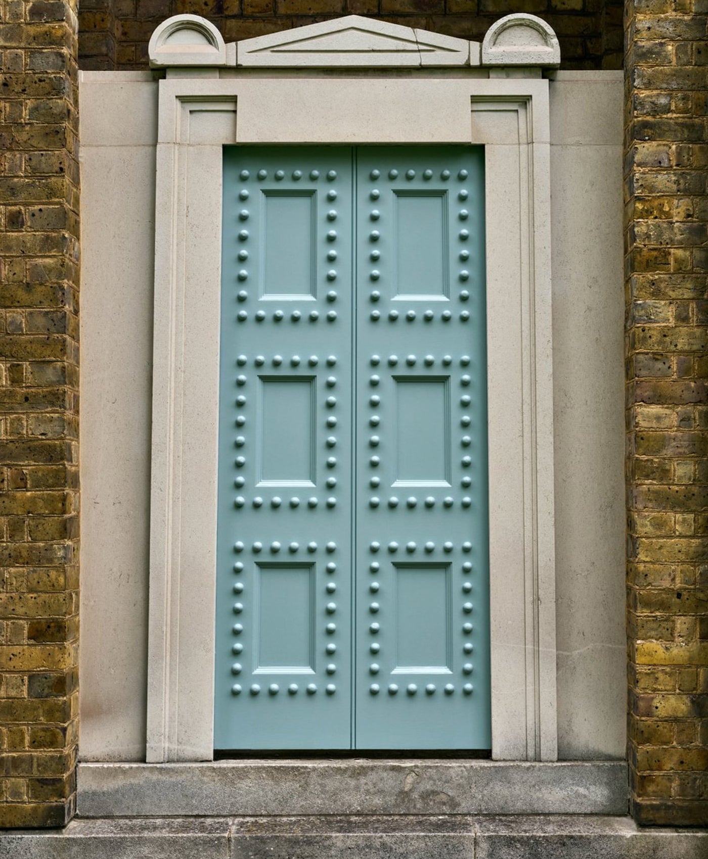 Light blue door with decorative patterns on a stone and brick wall.