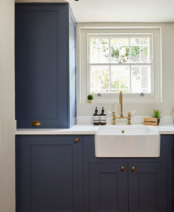 Modern kitchen with navy blue cabinets, white countertop, and gold fixtures.