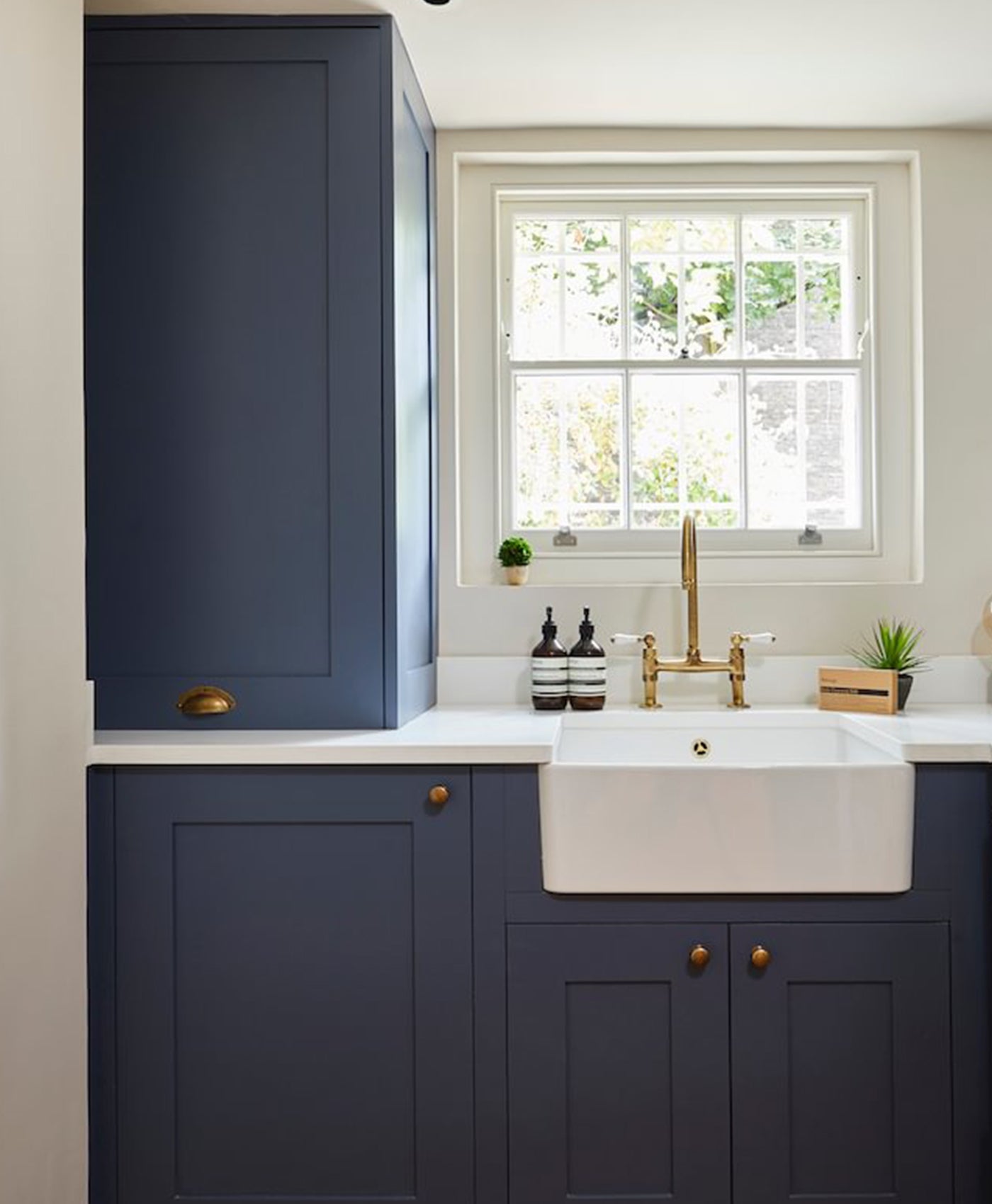 Modern kitchen with navy blue cabinets, white countertop, and gold fixtures.