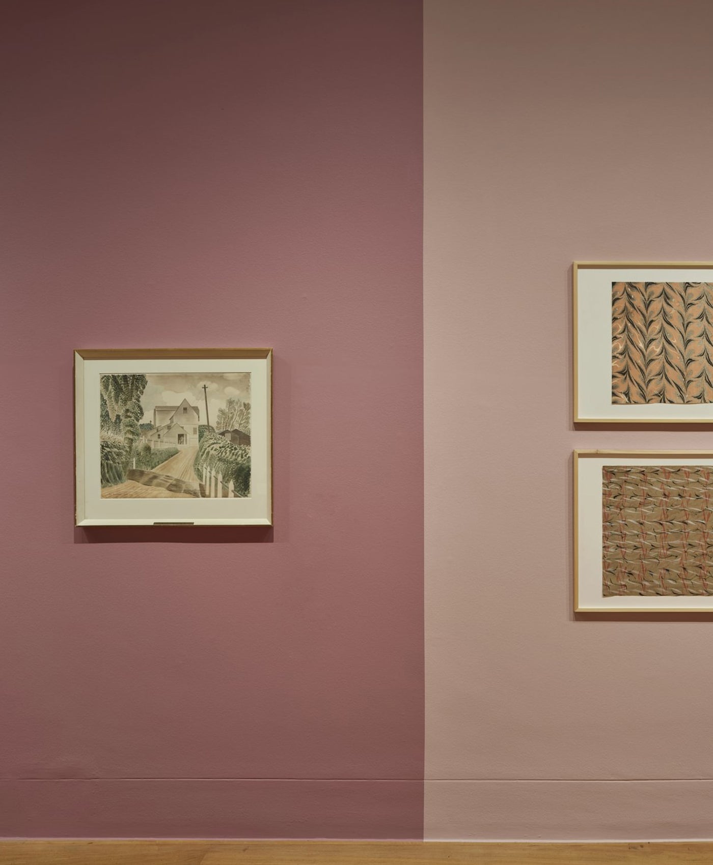 Three framed artworks on a wall with a dusty pink two-tone color scheme.