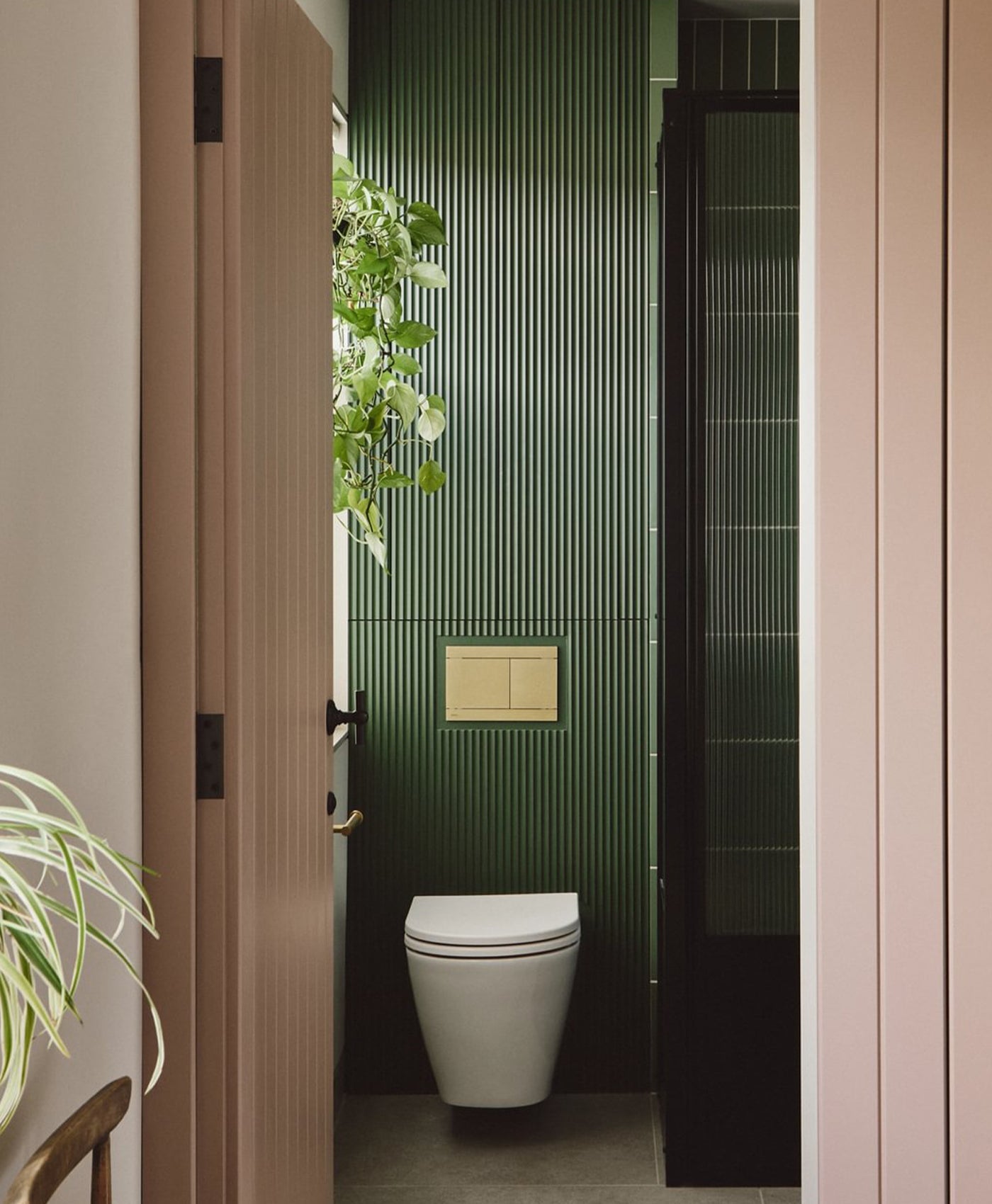 Bathroom with dark green tiled wall and white toilet