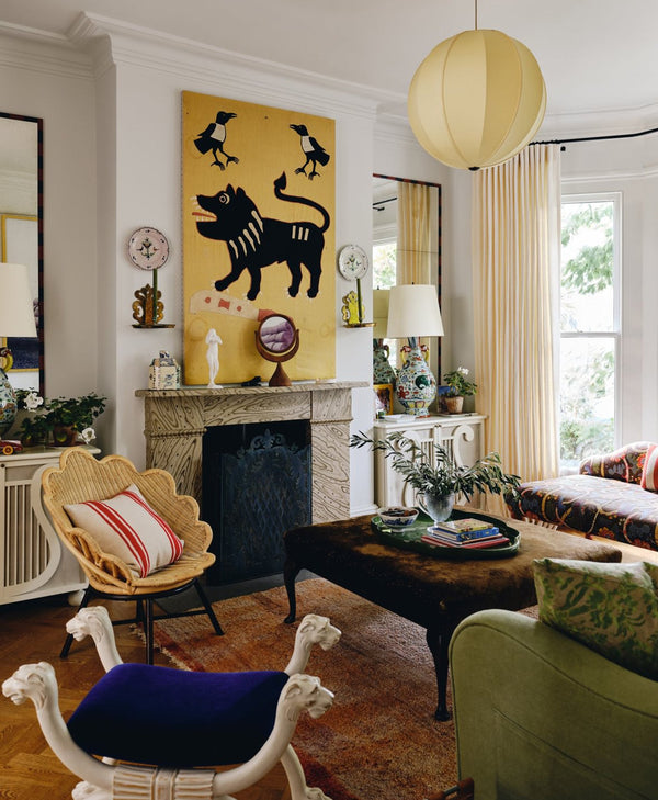 Beata Heuman's living room painted in off-white paint with a fireplace, artwork, and decorative items.