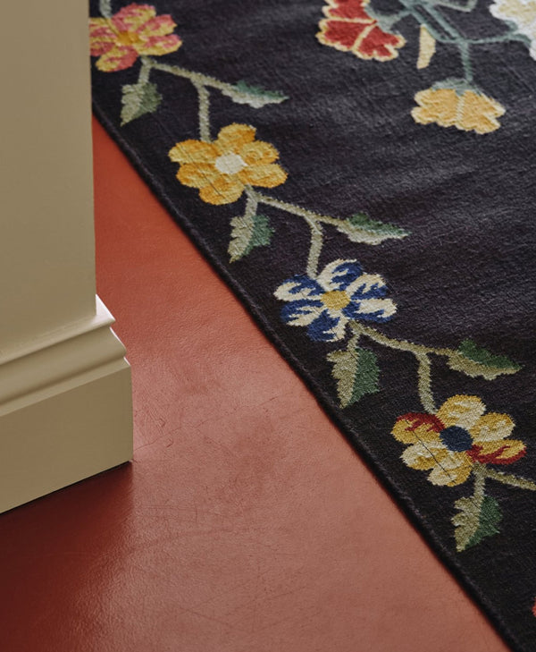 Floral-patterned rug corner on a terracotta red floor