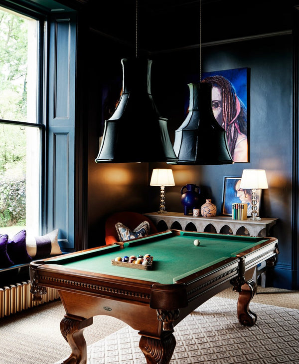 Dark blue games room with pool table, decorative lamps, and wall art.