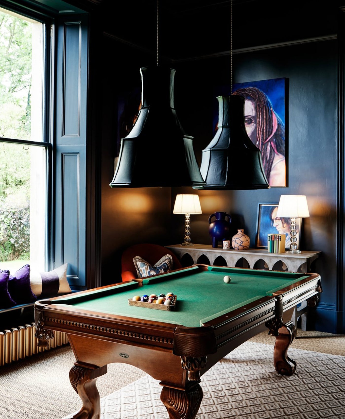 Dark blue games room with pool table, decorative lamps, and wall art.