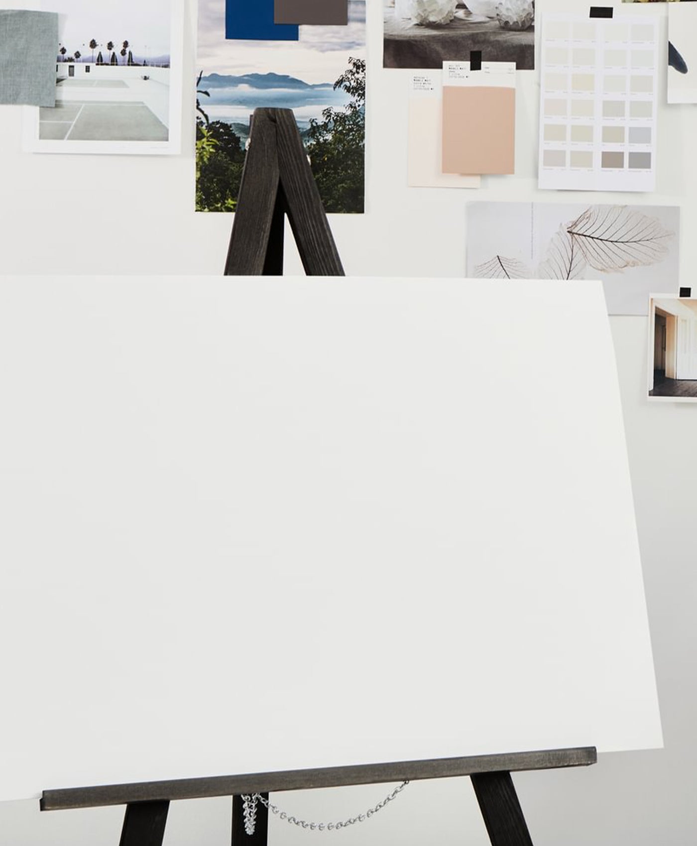 White canvas on an easel with various images and color swatches displayed on a white wall.