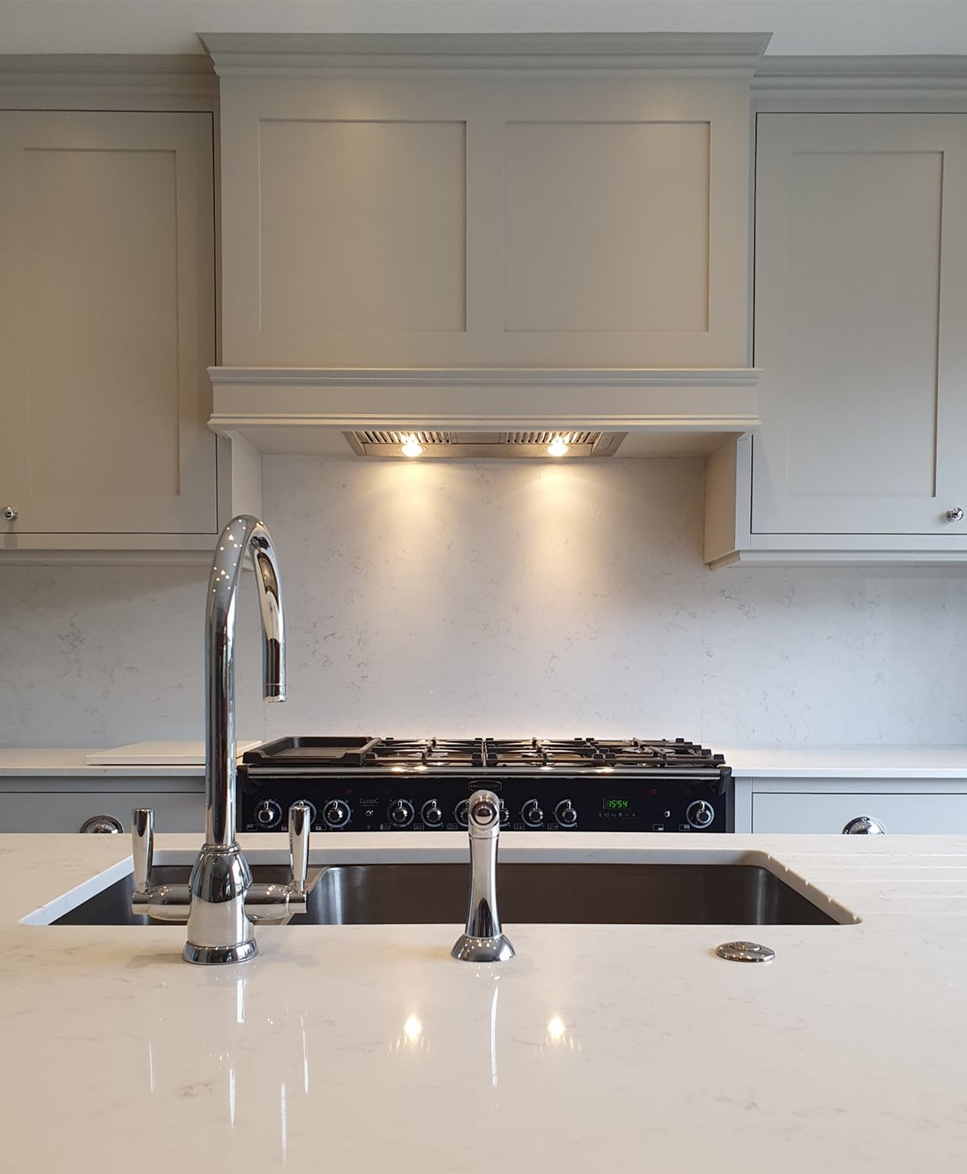 light grey modern kitchen with pale grey cabinets, stainless steel appliances, and a marble countertop.