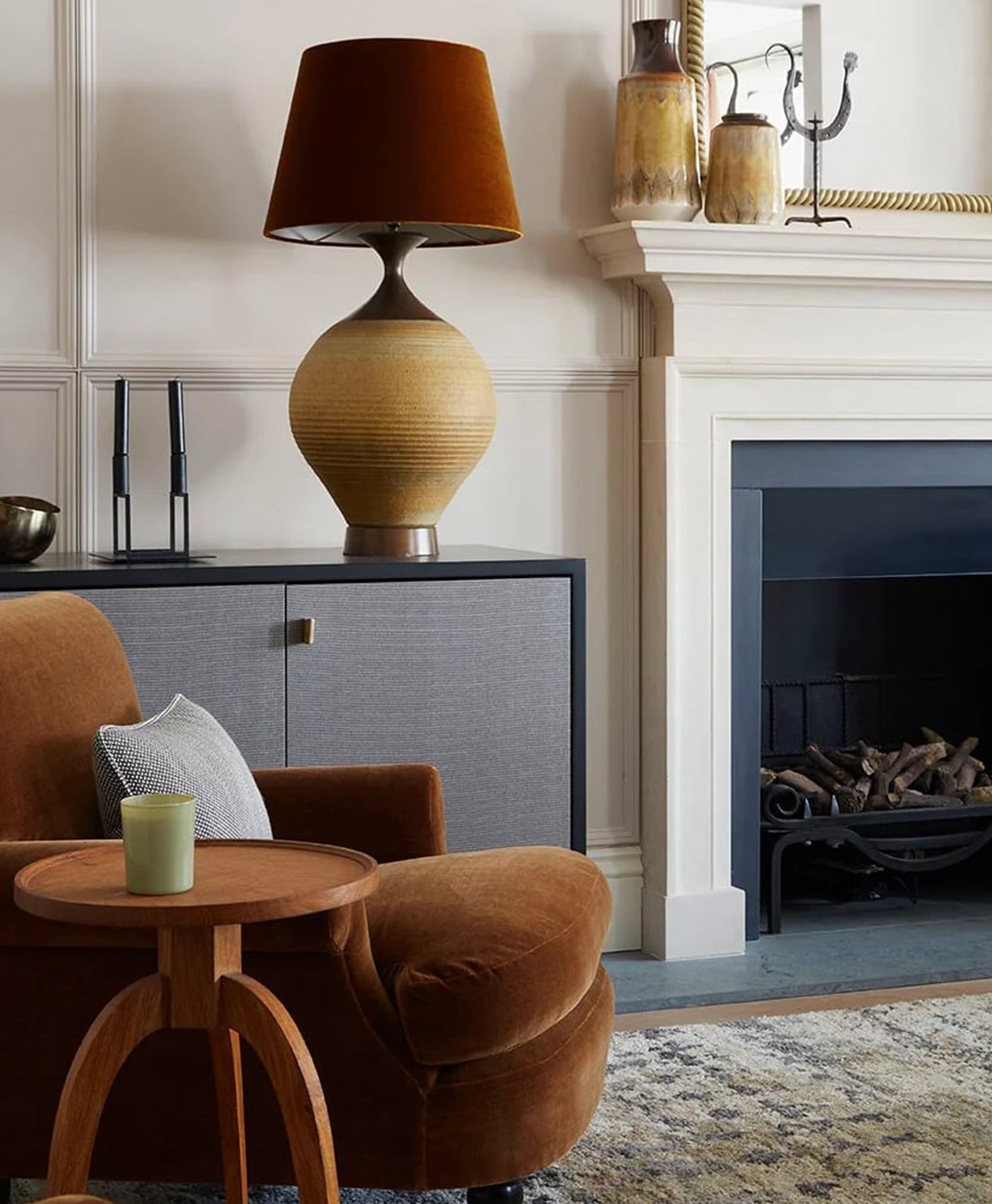 Cosy neutral living room with brown armchair, lamp, and fireplace.