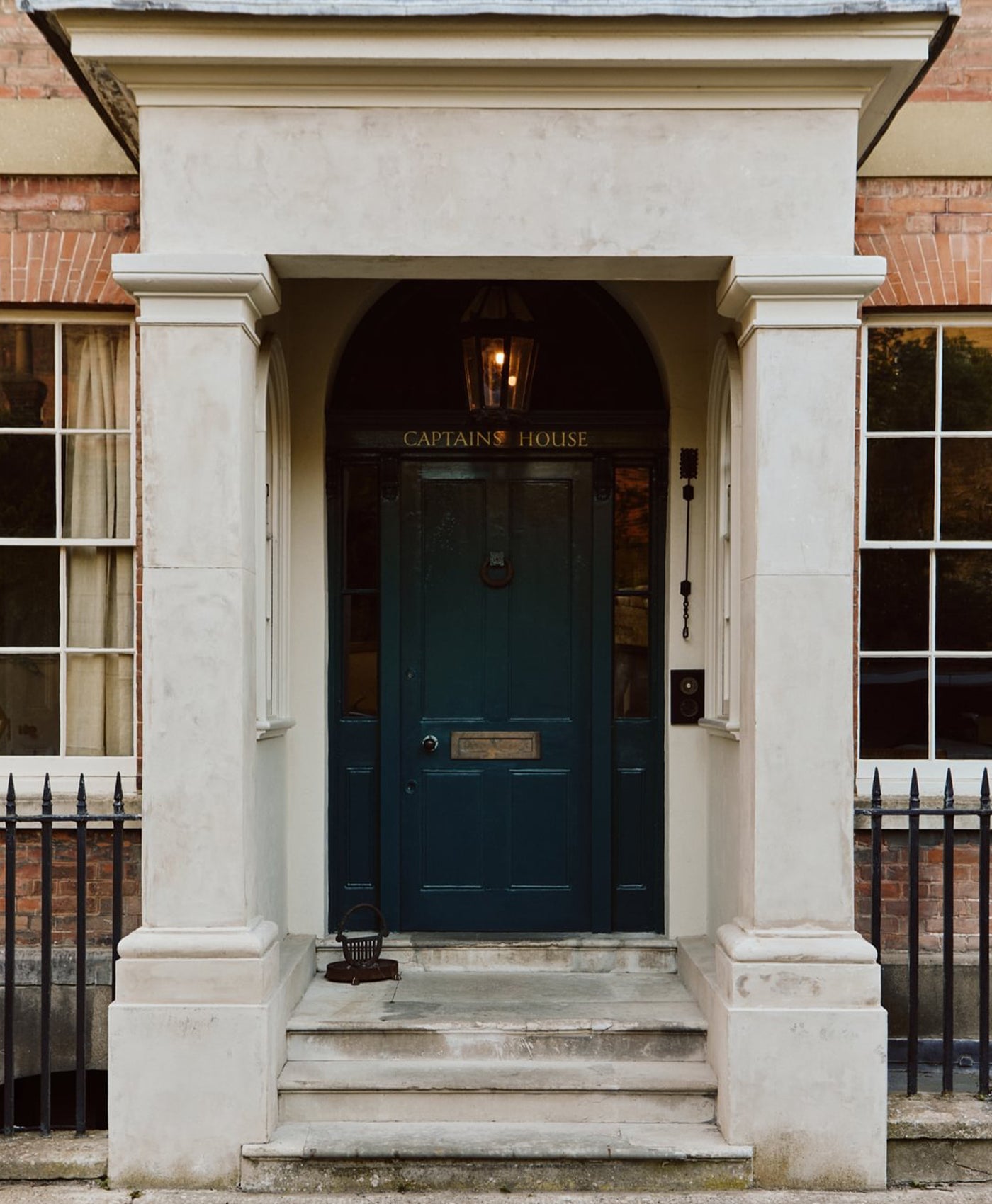 Portico of a building with a dark blue door and 'Captain's House' sign.