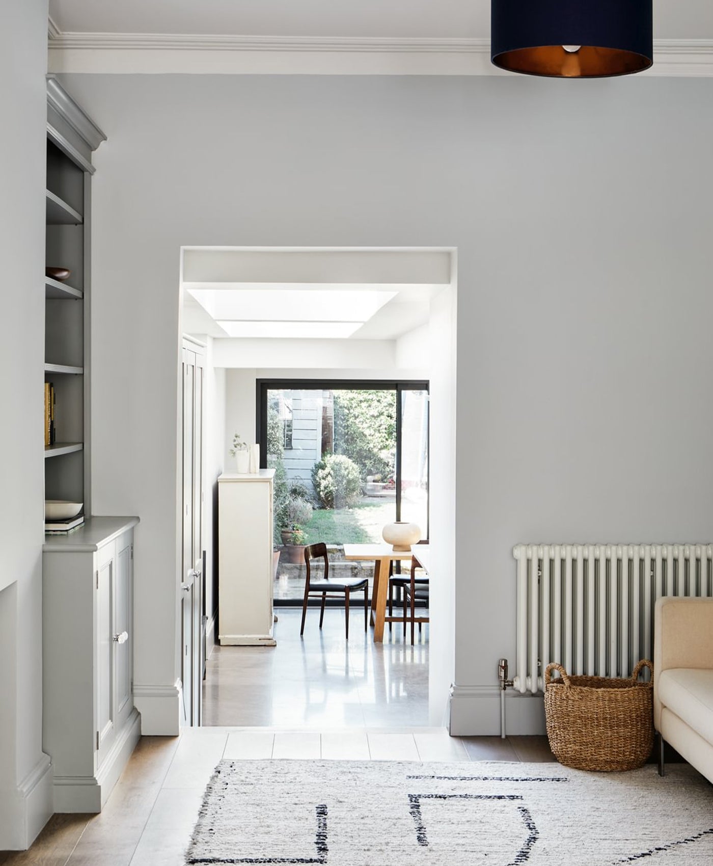Modern interior with grey walls, white ceiling, and a view into a bright room with furniture.