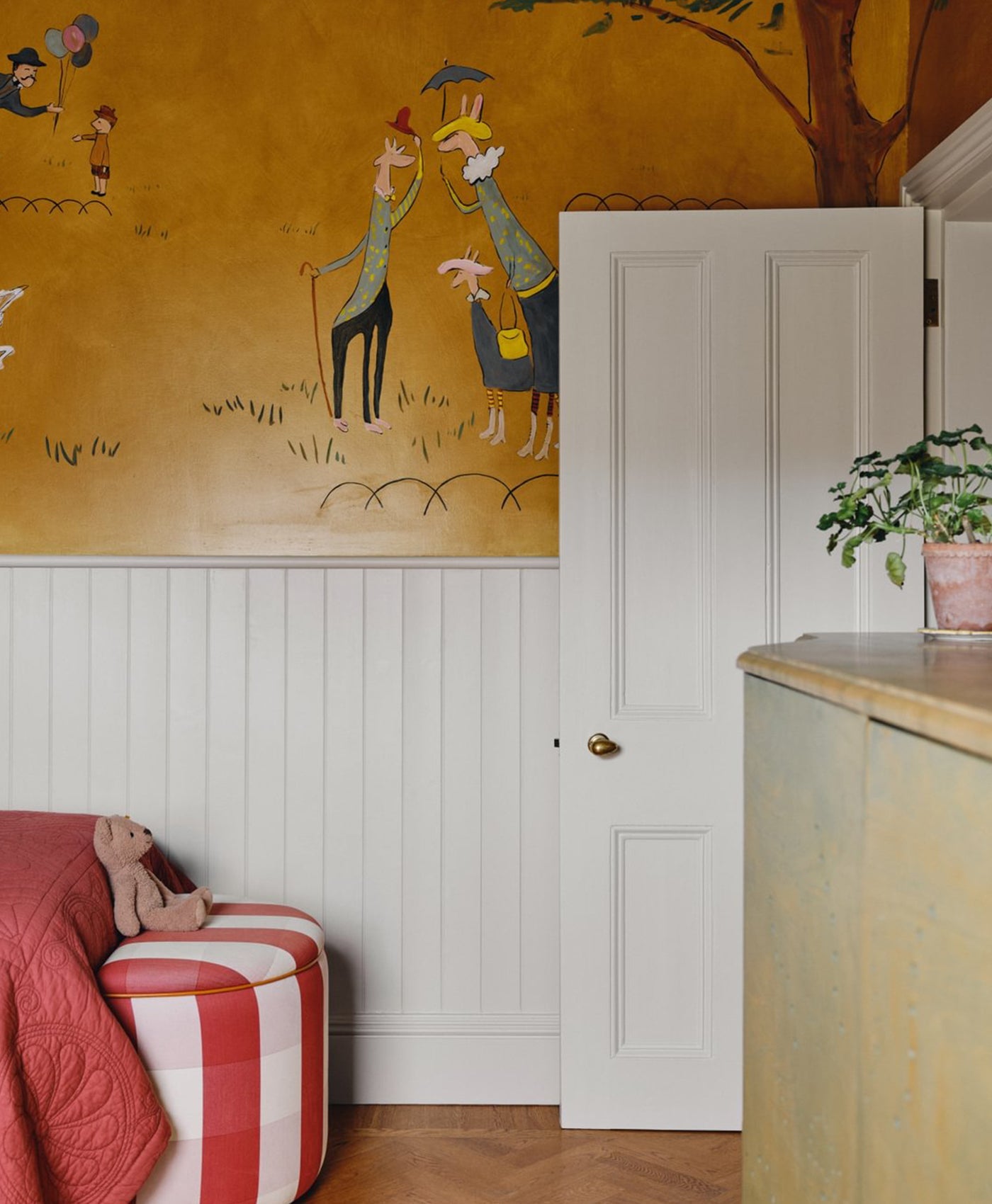 Children's room with a mural on the wall, a white door and wooden panelling