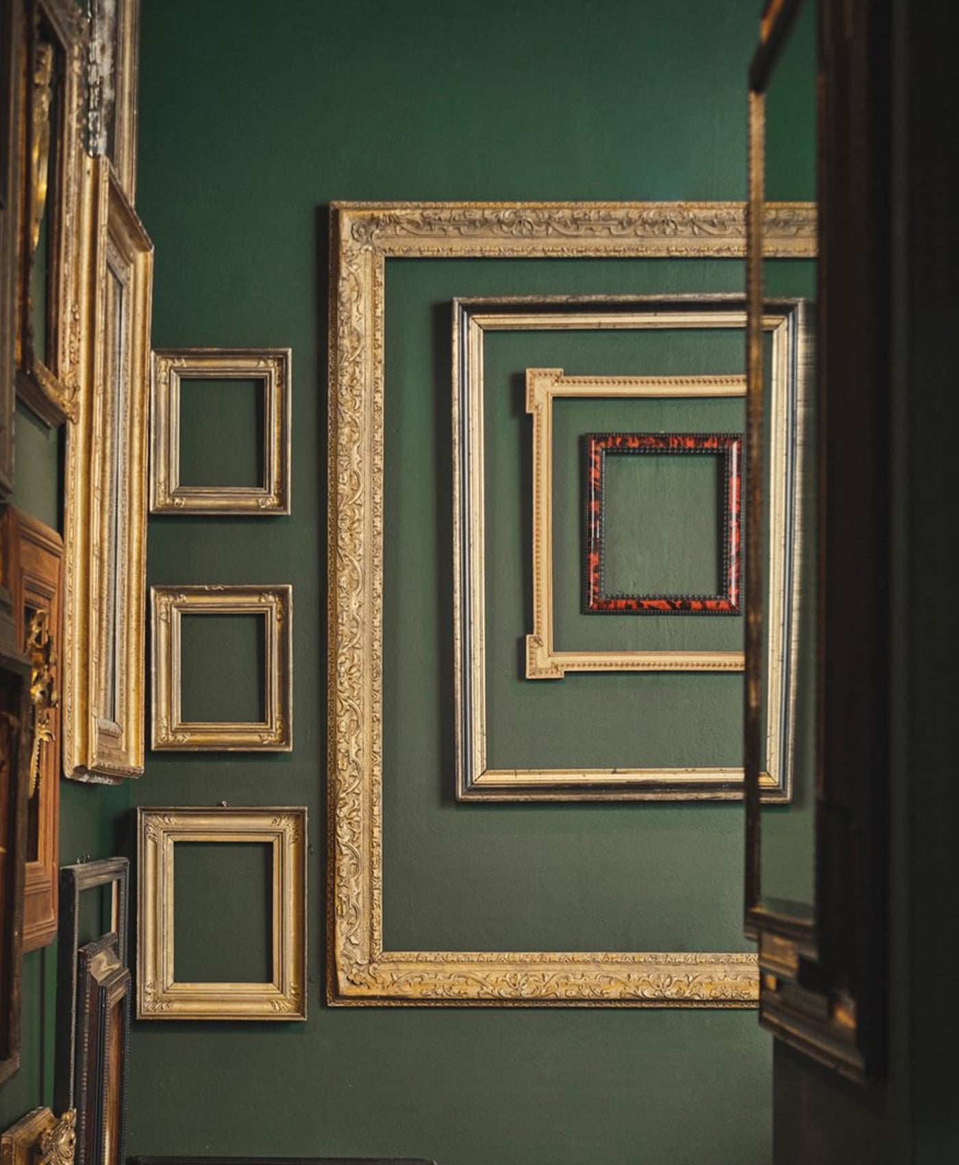 Collection of gold picture frames on a bottle green wall
