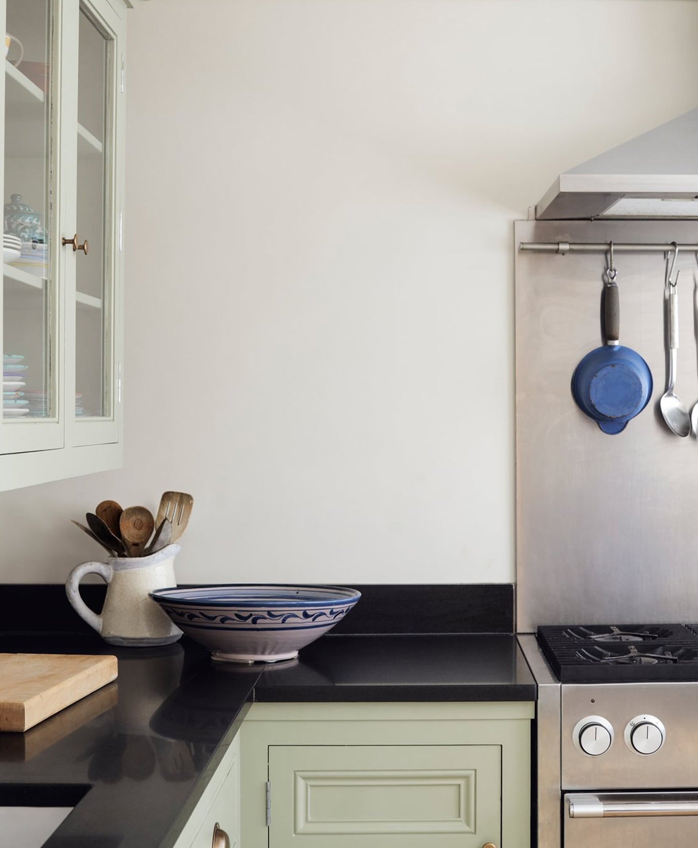 Snow white modern kitchen with black countertops, green cabinets, and stainless steel appliances.