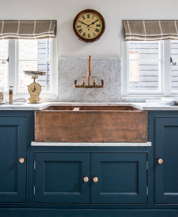 Snow white kitchen with copper farmhouse sink and blue cabinets