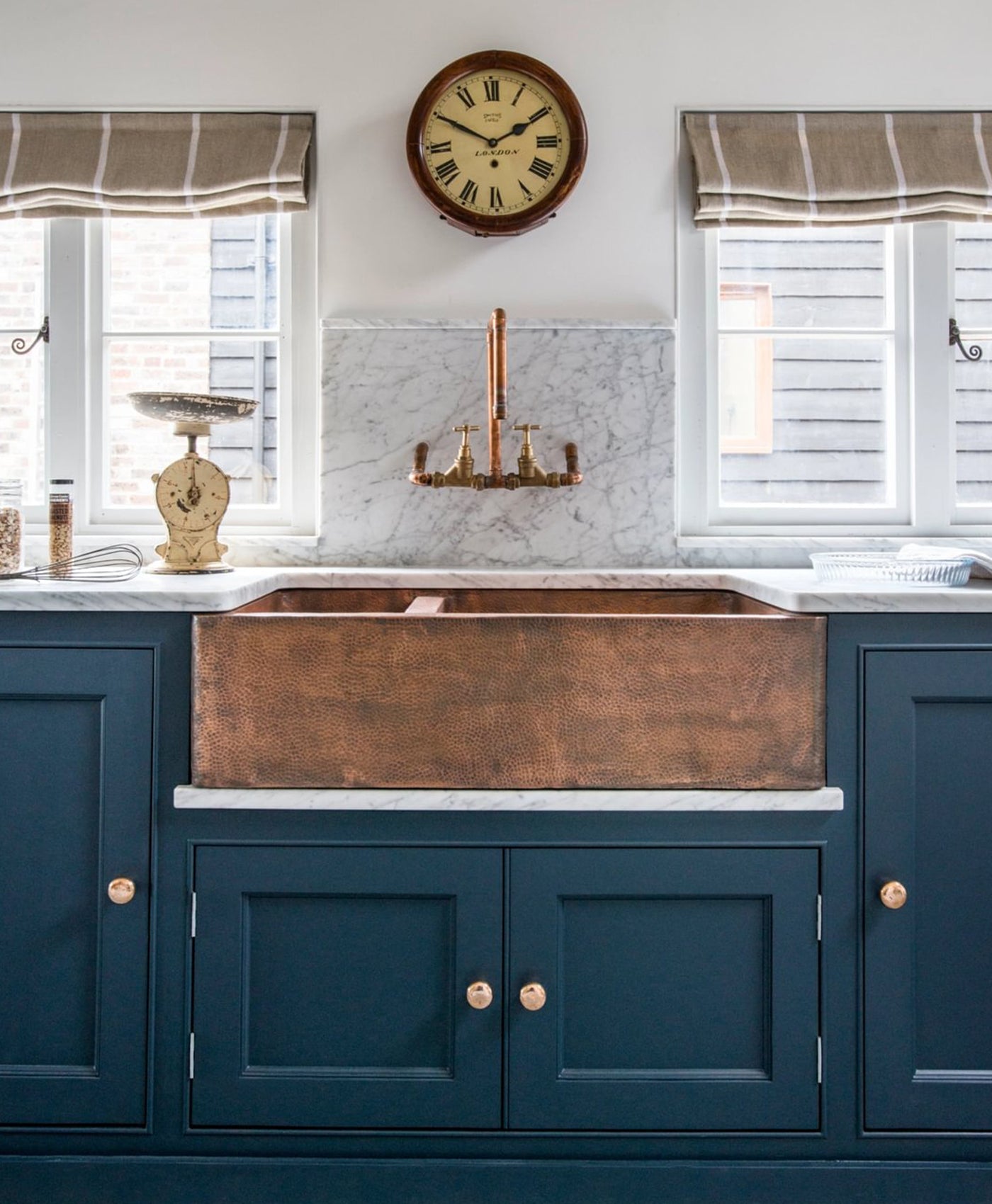 Snow white kitchen with copper farmhouse sink and blue cabinets