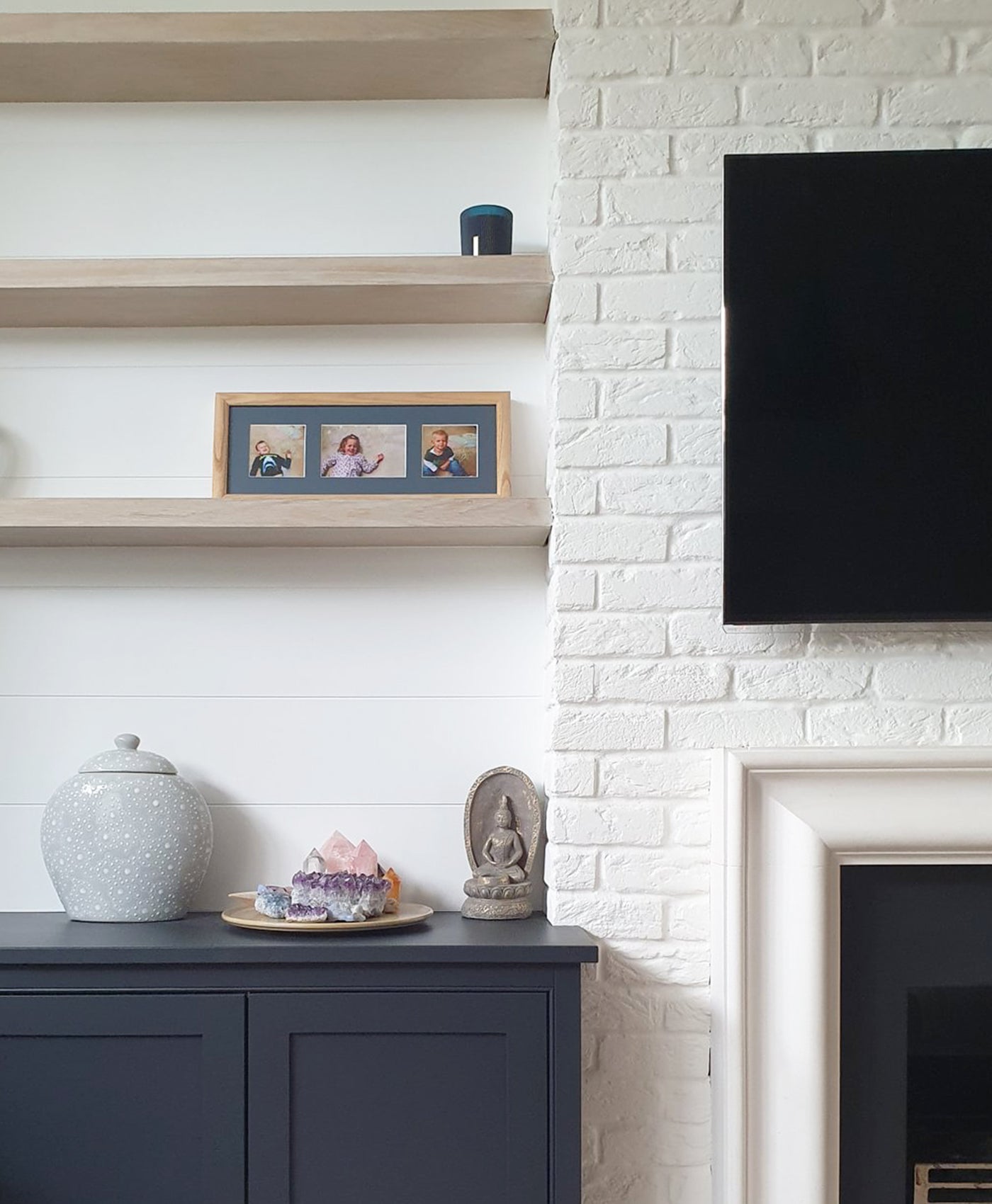 living room with whote brick painted chimney breast and navy painted cabinets