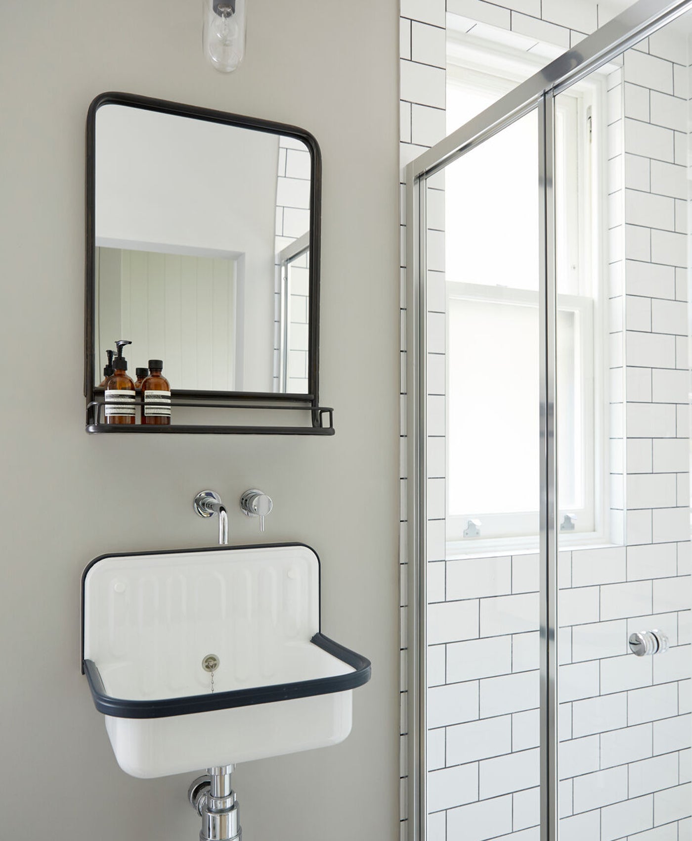 Grey bathroom with a sink, mirror, and shower area.