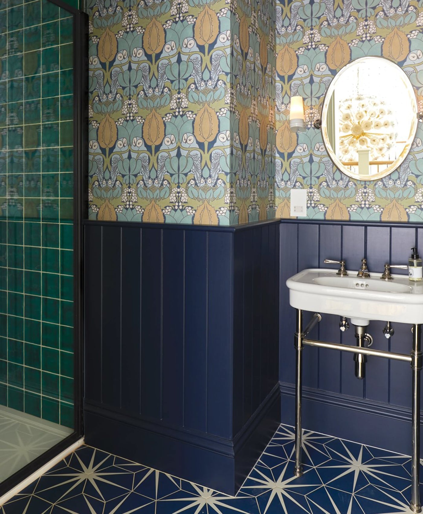 Bathroom with patterned wallpaper, dark blue panelling, and a white sink.