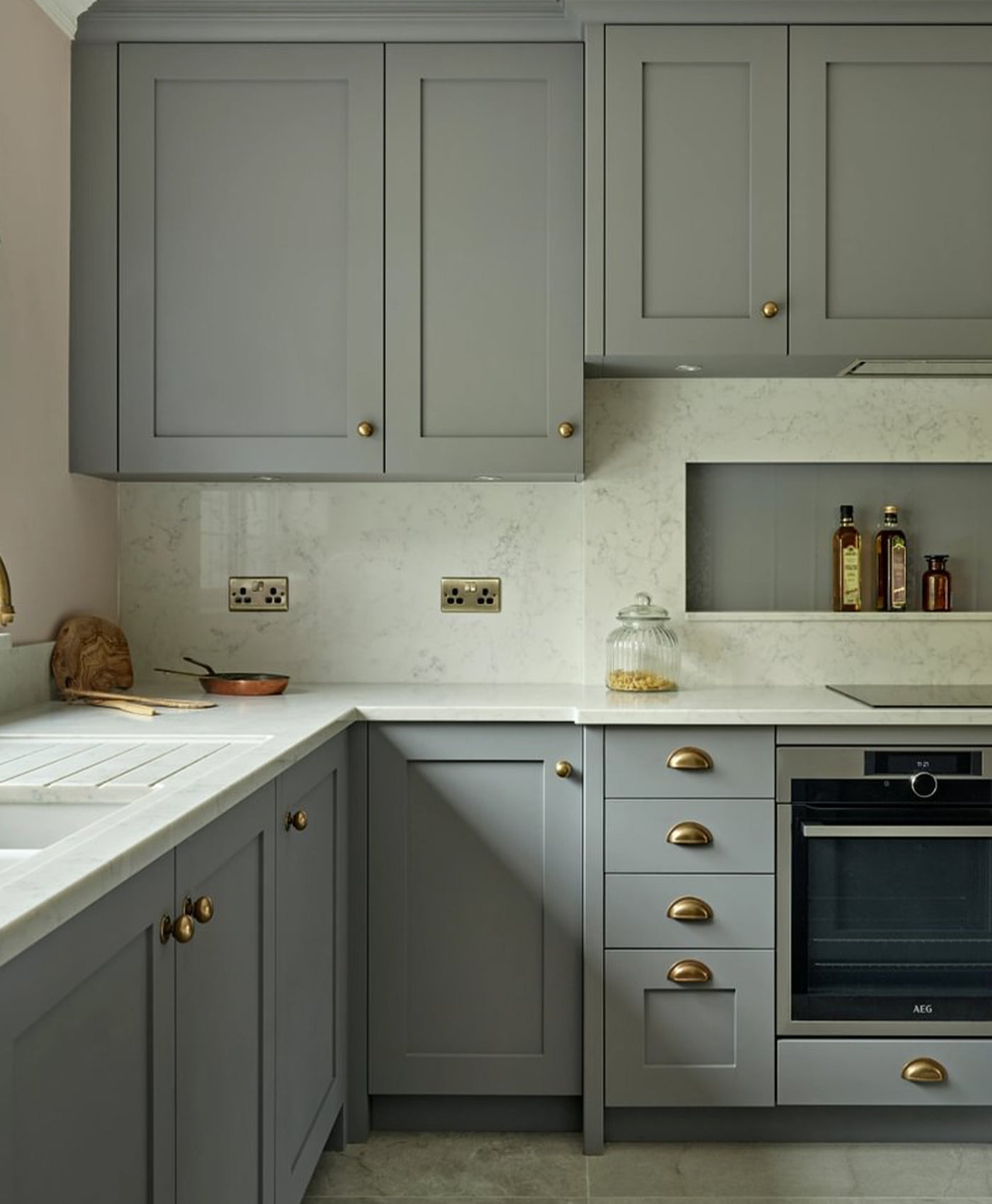 Battleship grey cabinets in modern kitchen with marble countertops and brass handles