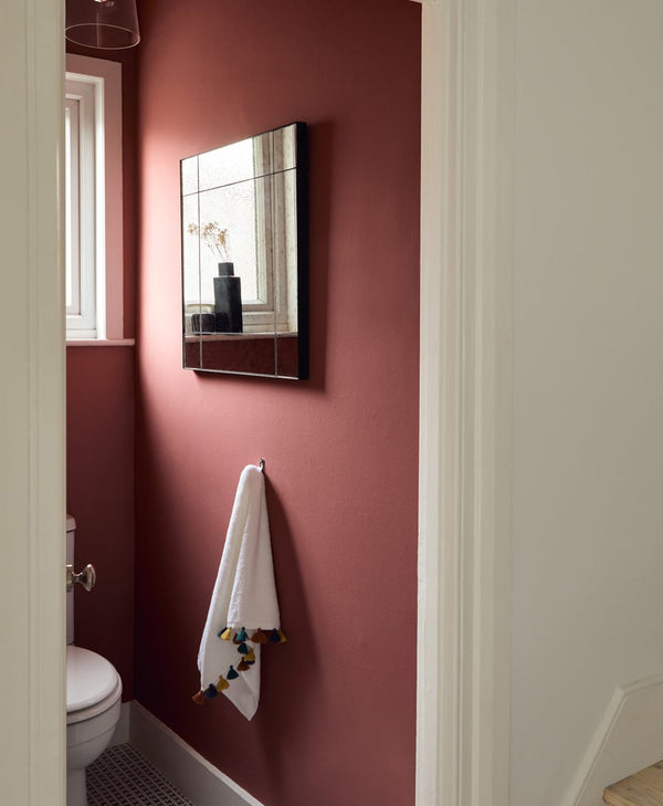 Bathroom with red pink wall, mirror, and white towel