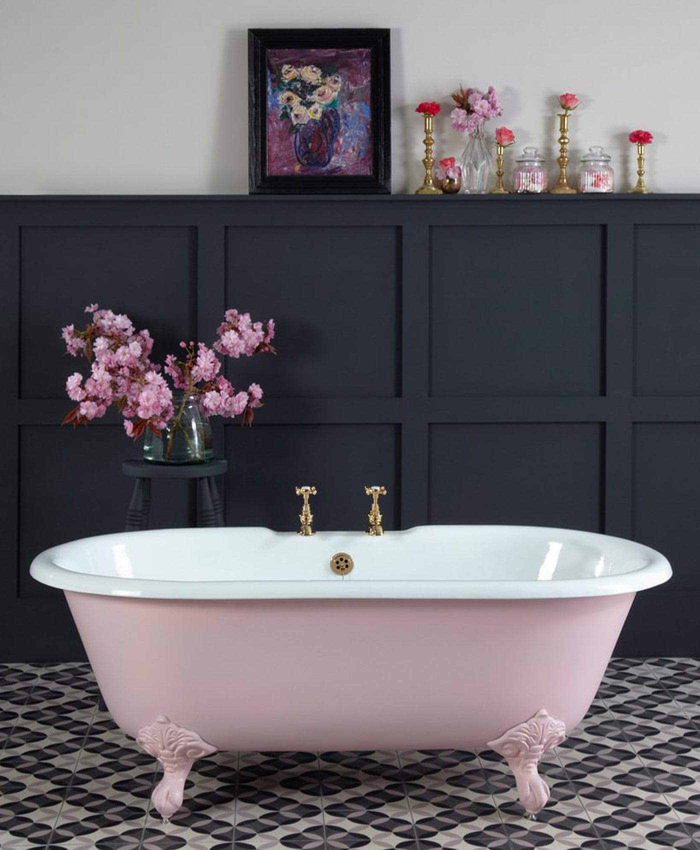 Pink freestanding bathtub in a bathroom with dark paneling and decorative elements.