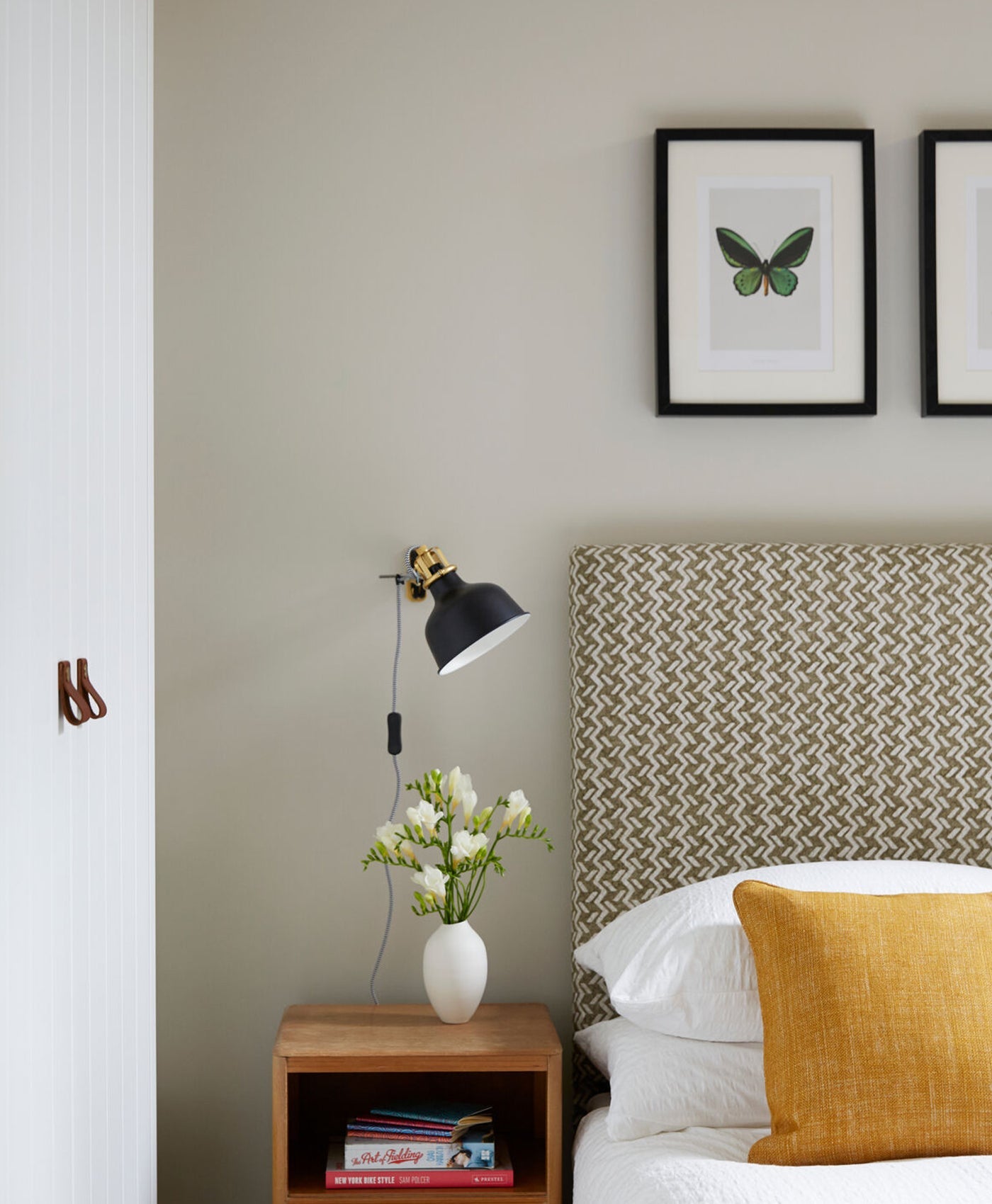 Neutral green toned bedroom room with a bed, nightstand, and wall art.